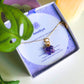 Handmade amethyst clover necklace with gold wire wrapping in aesthetic flat lay styling with candle and plant, beautifully presented in Laganna jewelry box - healing crystal jewelry crafted by Sri Lankan artisan for calm and spiritual balance
