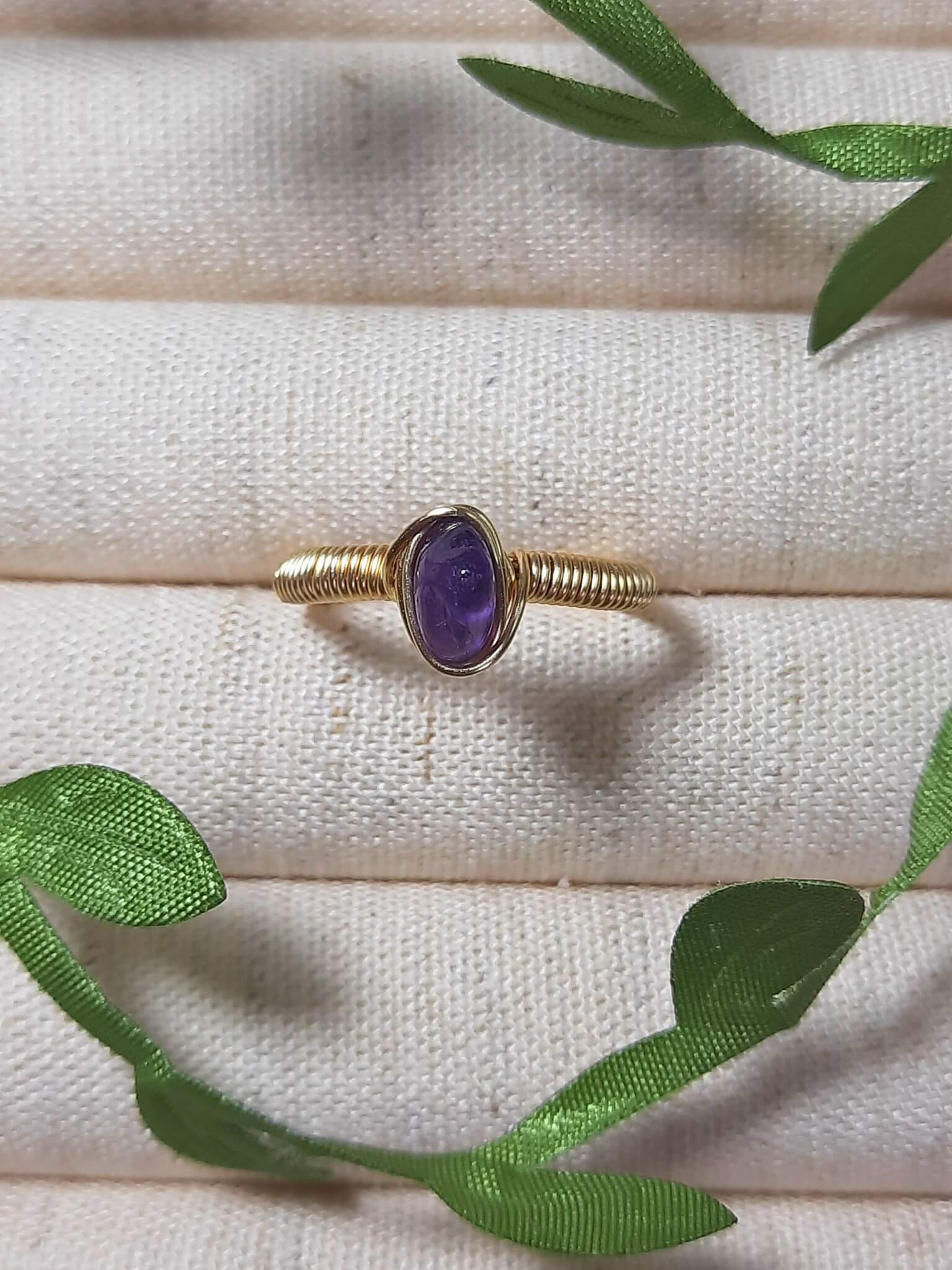 Natural amethyst irregular stone ring on jewelry display showing handmade gold wire wrapped healing crystal jewelry, Sri Lankan artisan spiritual ring with raw purple gemstone perfect as boho stress relief ring and third eye chakra amulet for meditation and tranquility