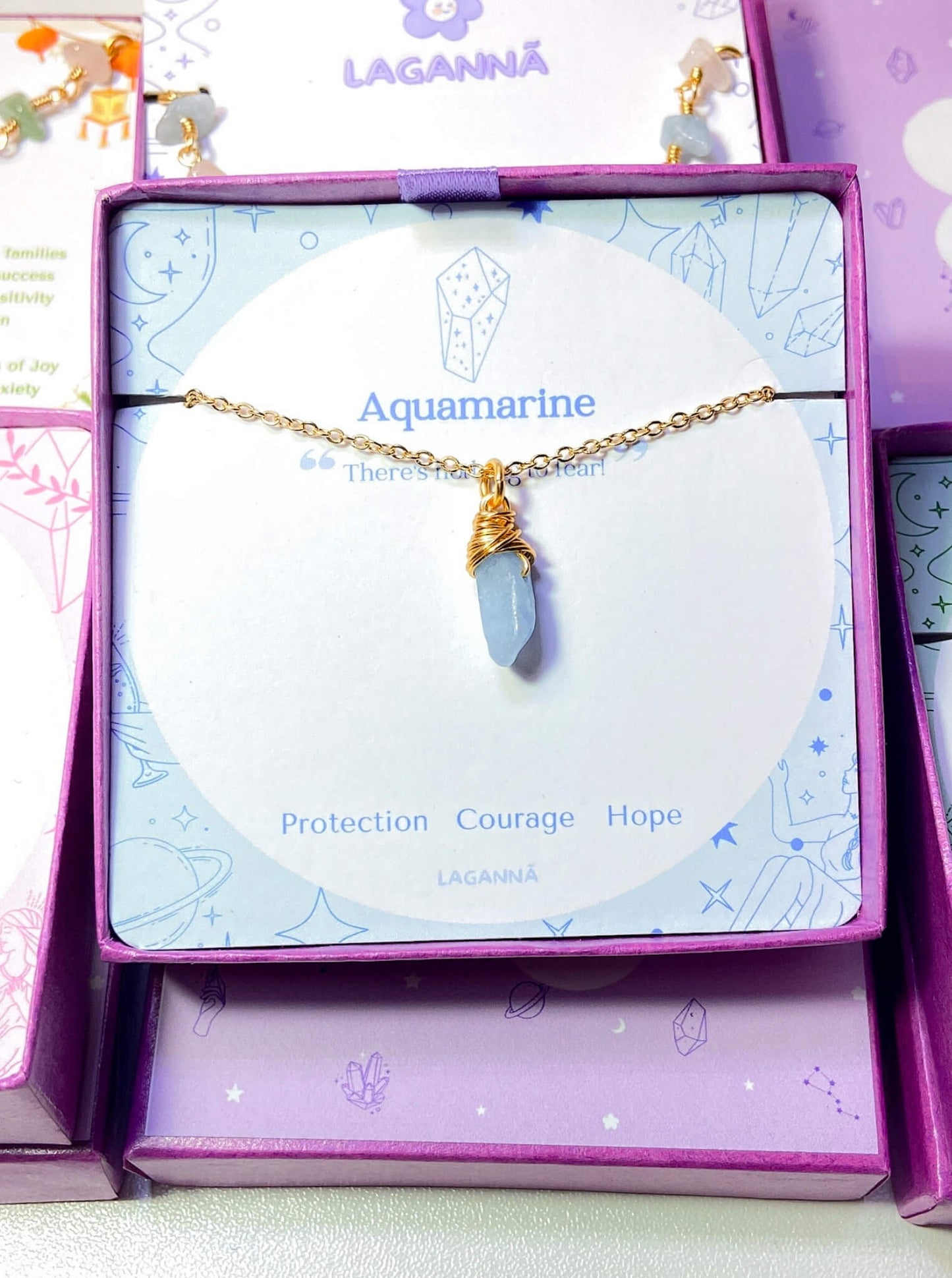 Aquamarine irregular stone necklace jewelry box front view showing gold wire wrapped design, handmade Sri Lankan healing crystal pendant for clarity and calm