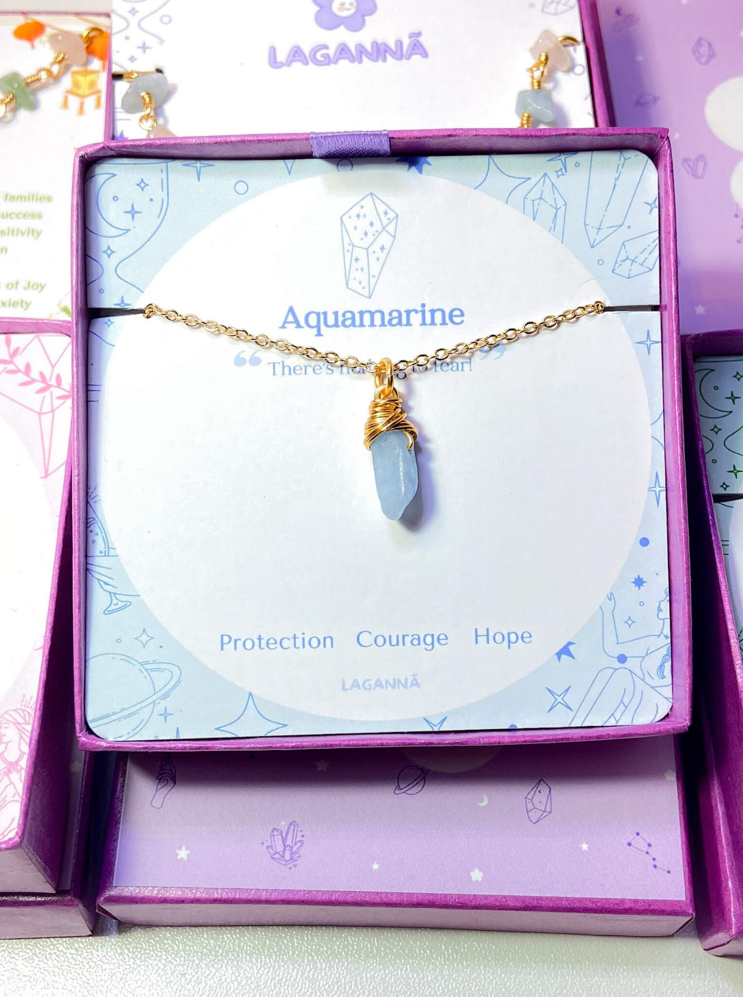 Aquamarine irregular stone necklace jewelry box front view showing gold wire wrapped design, handmade Sri Lankan healing crystal pendant for clarity and calm