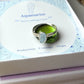 Aquamarine Irregular Stone Ring silver wire wrapped resting on green glass stone prop over Laganna crystal meaning card showing Protection Courage Hope, handmade healing crystal ring Sri Lanka – throat chakra clarity courage
