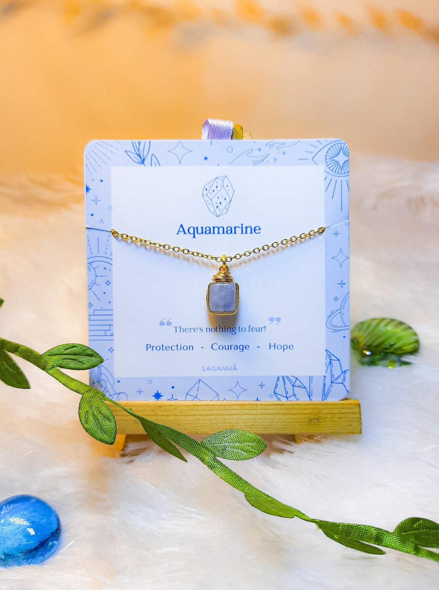 Handmade aquamarine square stone necklace in gold wire wrapped design on jewelry card featuring natural healing crystal jewelry crafted by Sri Lankan artisans as throat chakra balancing pendant and communication enhancement amulet for women seeking clarity and emotional healing with geometric blue gemstone