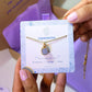 Aquamarine square stone necklace jewelry card held in hand showing handmade gold wire wrapped healing crystal gift set, Sri Lankan artisan throat chakra pendant featuring natural square blue gemstone perfect as communication jewelry gift for clarity and tranquility with elegant presentation