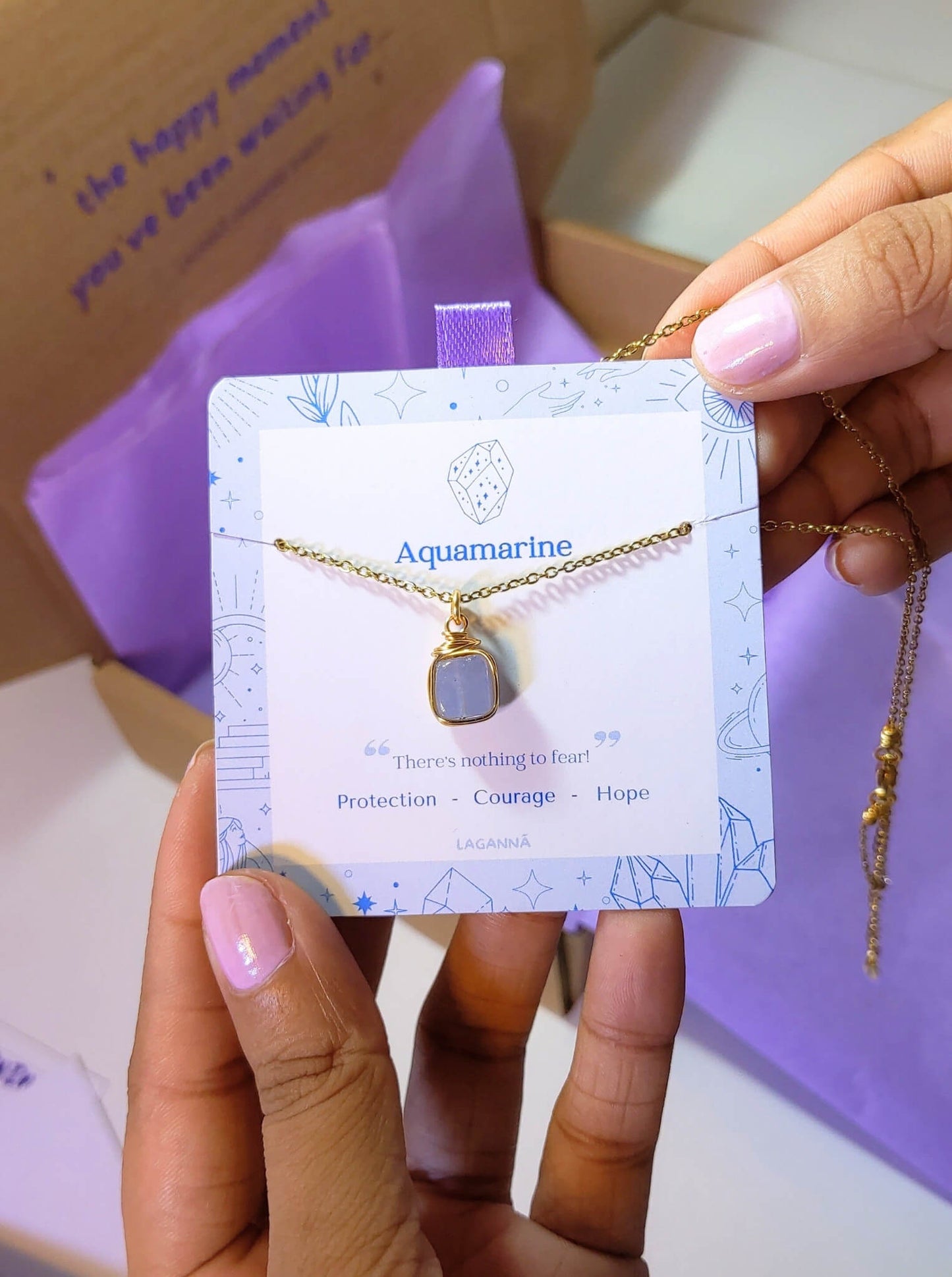 Aquamarine square stone necklace jewelry card held in hand showing handmade gold wire wrapped healing crystal gift set, Sri Lankan artisan throat chakra pendant featuring natural square blue gemstone perfect as communication jewelry gift for clarity and tranquility with elegant presentation