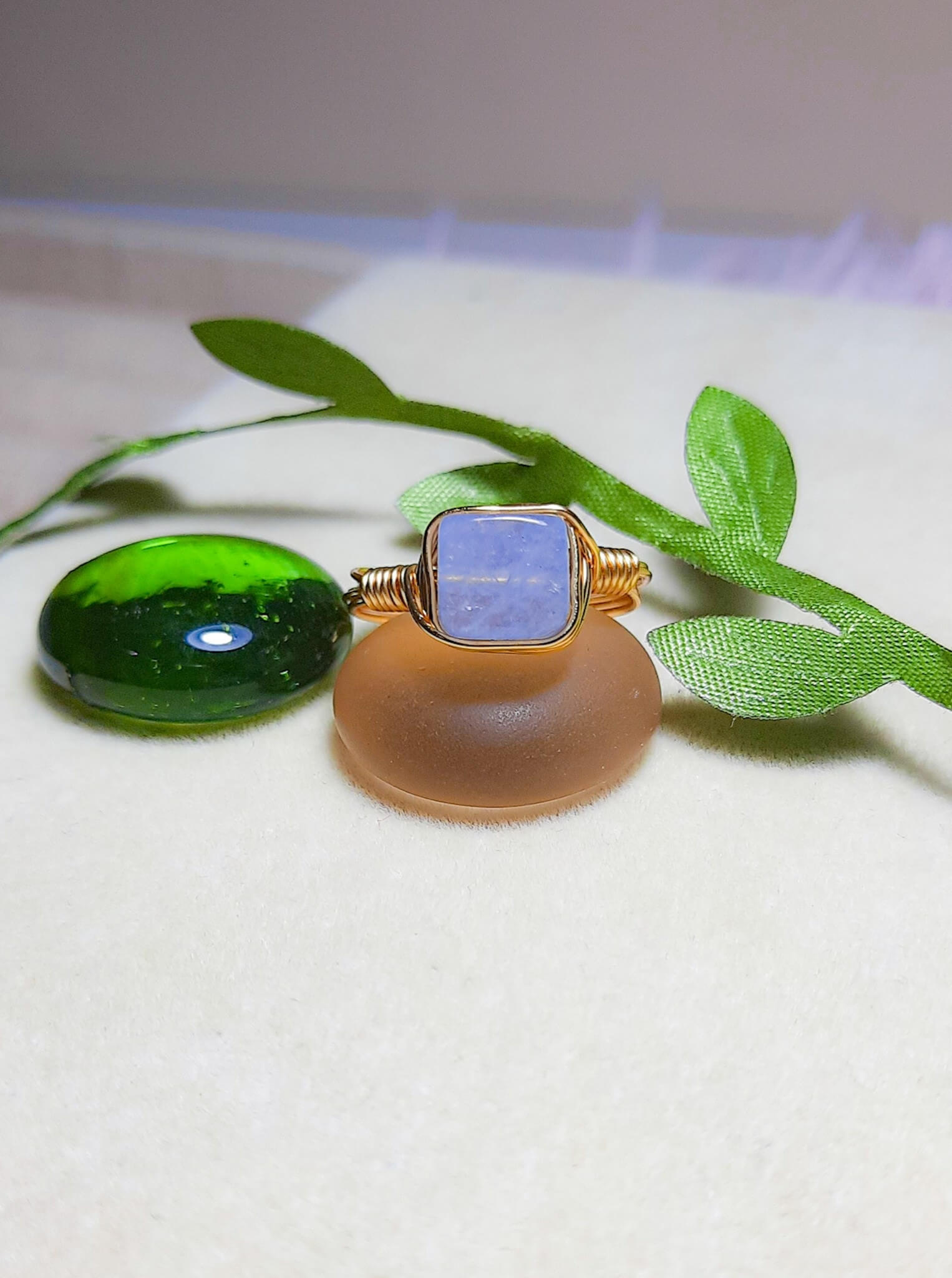 Handmade aquamarine square stone ring in gold wire wrap on jewelry display, Sri Lankan healing crystal jewelry for throat chakra balancing and communication enhancement