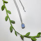 Natural aquamarine square stone necklace on white background showing handmade silver wire wrapped healing crystal jewelry, Sri Lankan artisan throat chakra pendant featuring geometric blue gemstone perfect as boho communication necklace and calming amulet for emotional balance and peace