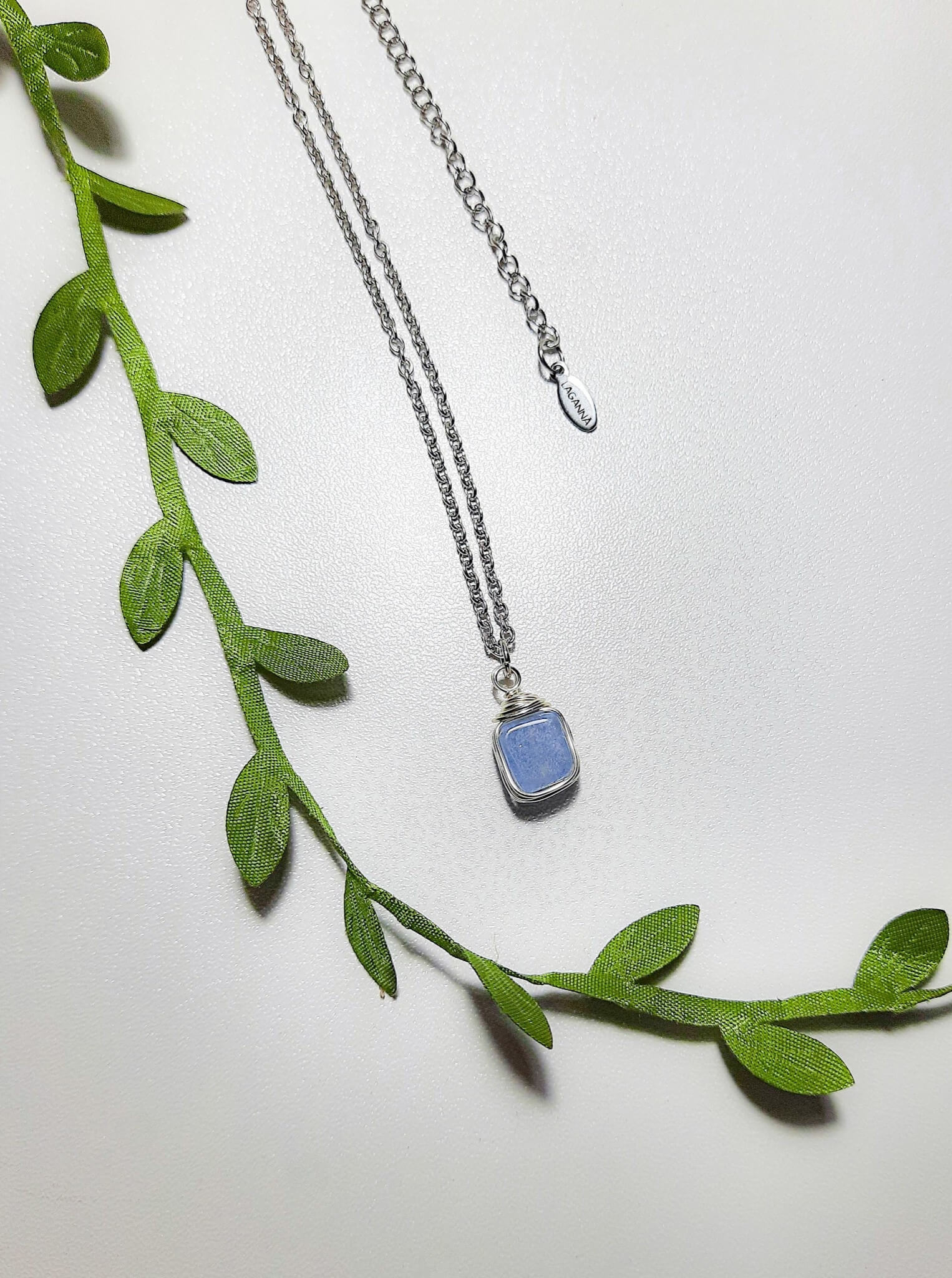 Natural aquamarine square stone necklace on white background showing handmade silver wire wrapped healing crystal jewelry, Sri Lankan artisan throat chakra pendant featuring geometric blue gemstone perfect as boho communication necklace and calming amulet for emotional balance and peace