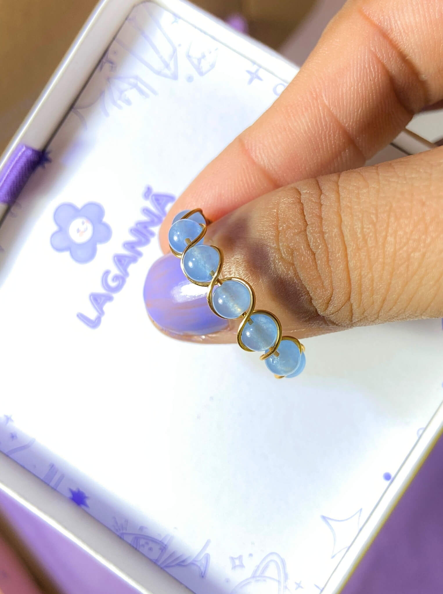 Blue chalcedony braided ring jewelry box held on hand closeup, handmade Sri Lankan gold wire wrapped healing crystal ring gift for calm and clarity