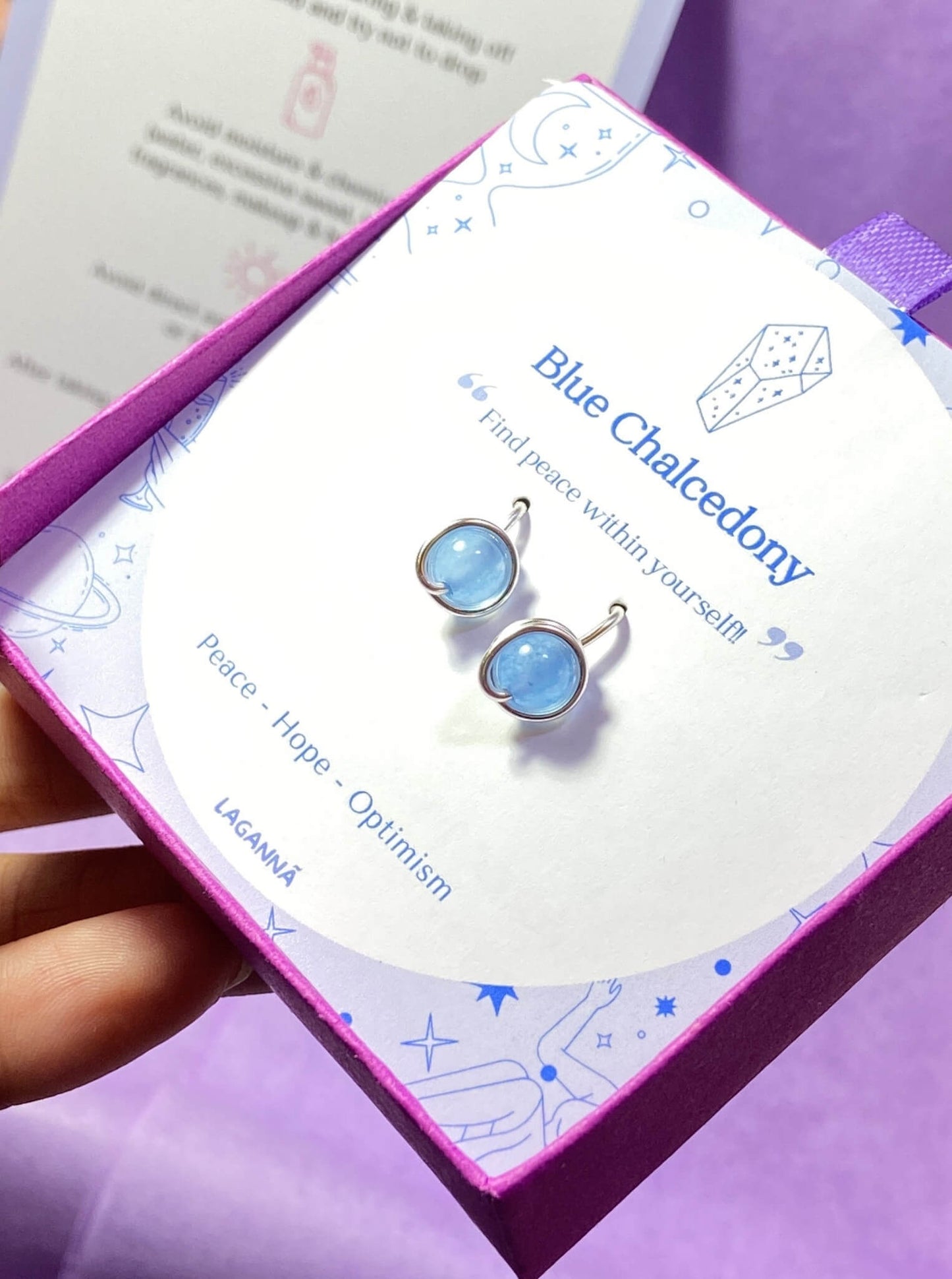 Two Blue Chalcedony Petite Round Stud Earrings on a laganna jewelry box showing wire-wrapped design and natural sky blue stones - handmade healing crystal jewelry from Sri Lanka