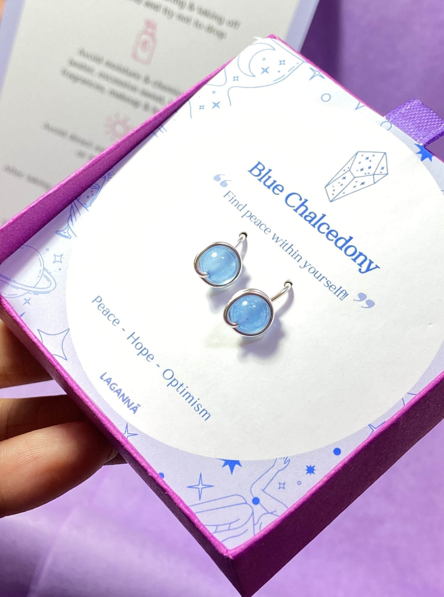 Two Blue Chalcedony Petite Round Stud Earrings on a laganna jewelry box showing wire-wrapped design and natural sky blue stones - handmade healing crystal jewelry from Sri Lanka
