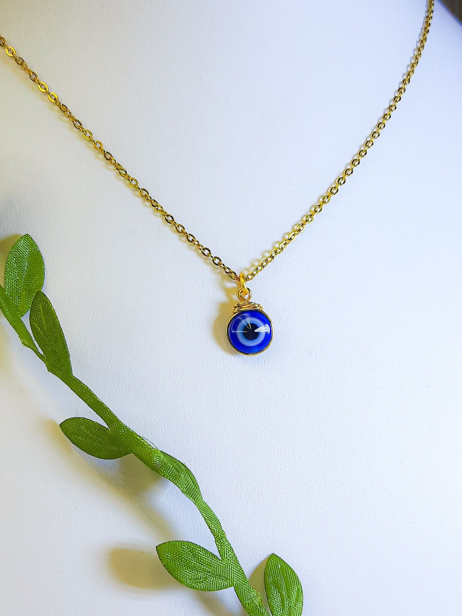 Gold blue evil eye protection necklace with natural green leaves showcasing adjustable spiritual pendant jewelry, handmade Sri Lankan healing crystal necklace with wire wrapped design perfect as boho evil eye talisman and protective amulet for nature-loving metaphysical enthusiasts