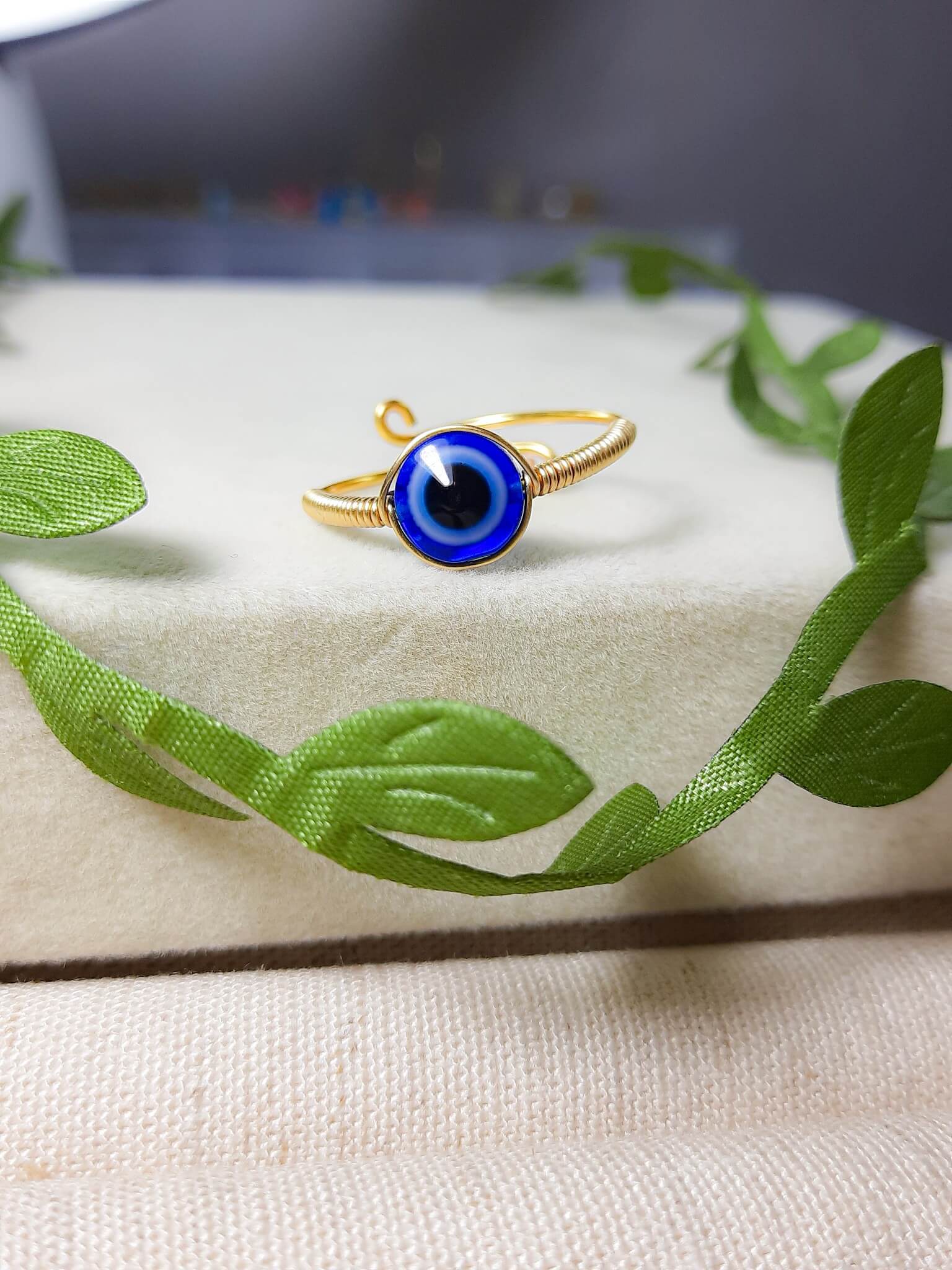 Blue evil eye ring with natural green leaves showcasing gold adjustable protection jewelry, handmade Sri Lankan spiritual ring with wire wrapped healing crystal design perfect as boho evil eye talisman and protective amulet for nature-loving metaphysical jewelry enthusiasts