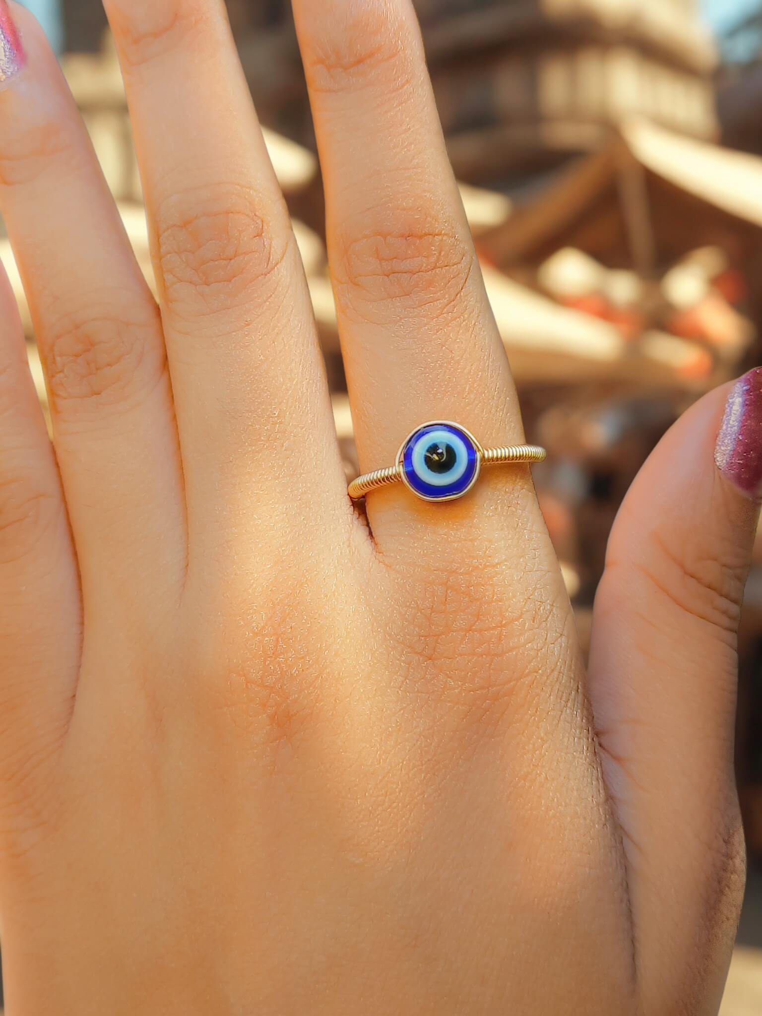 Blue evil eye ring worn on hand showing adjustable gold protection jewelry, handmade Sri Lankan spiritual ring with wire wrapped healing crystal design perfect as boho evil eye talisman and protective amulet for metaphysical jewelry lovers