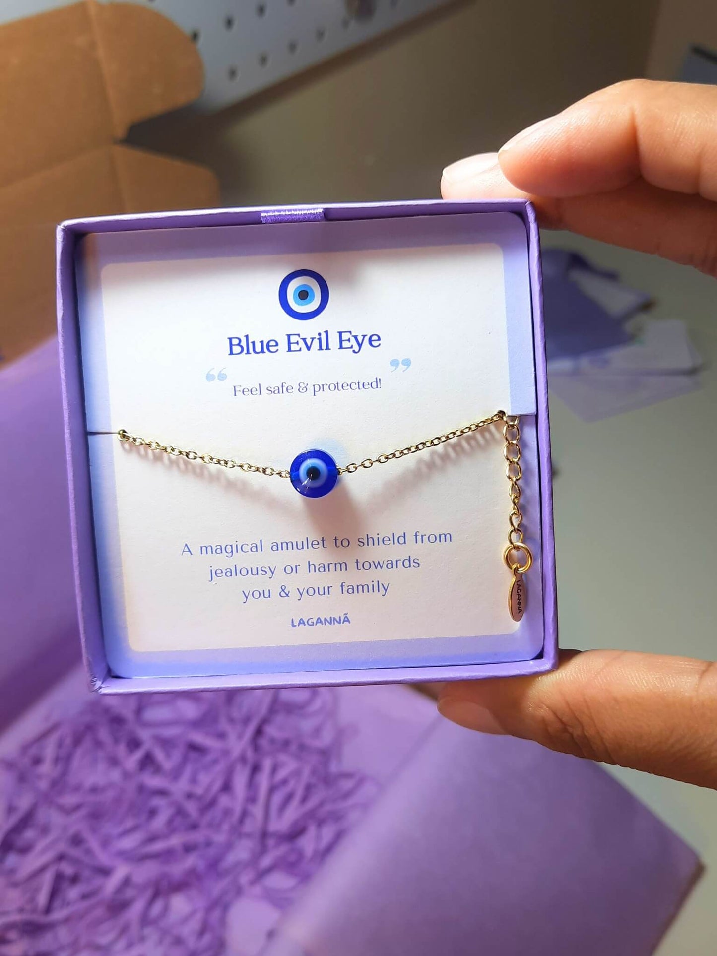 Blue evil eye bracelet jewelry box held in hand showing adjustable silver protection jewelry, handmade Sri Lankan spiritual bracelet with wire wrapped healing crystal design perfect as boho evil eye talisman and protective amulet for anxiety relief and metaphysical healing