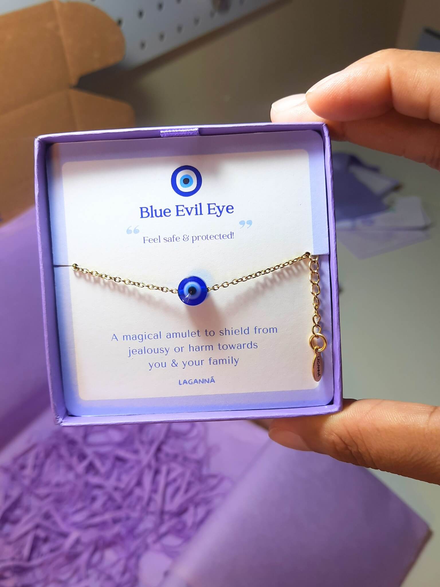 Blue evil eye bracelet jewelry box held in hand showing adjustable silver protection jewelry, handmade Sri Lankan spiritual bracelet with wire wrapped healing crystal design perfect as boho evil eye talisman and protective amulet for anxiety relief and metaphysical healing