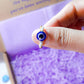 Blue evil eye seed bead ring held on hand showing gold wire wrapped design, handmade Sri Lankan protective talisman ring for warding off negative energy