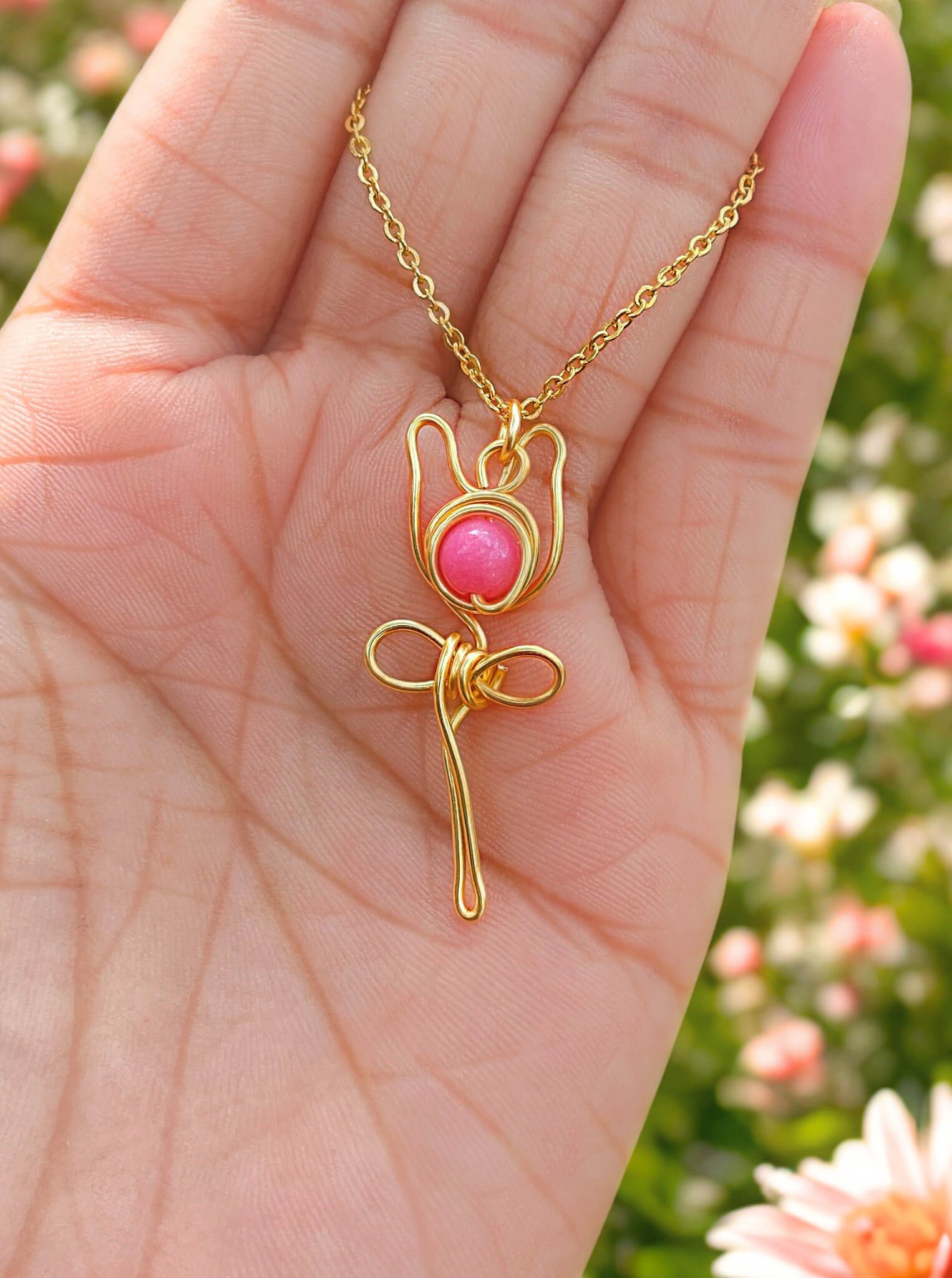 Elegant pink chalcedony rose pendant necklace presented on hand, showcasing minimalist gold wire wrapped design - handmade healing crystal jewelry from Sri Lanka for the modern feminine woman seeking self-love accessories