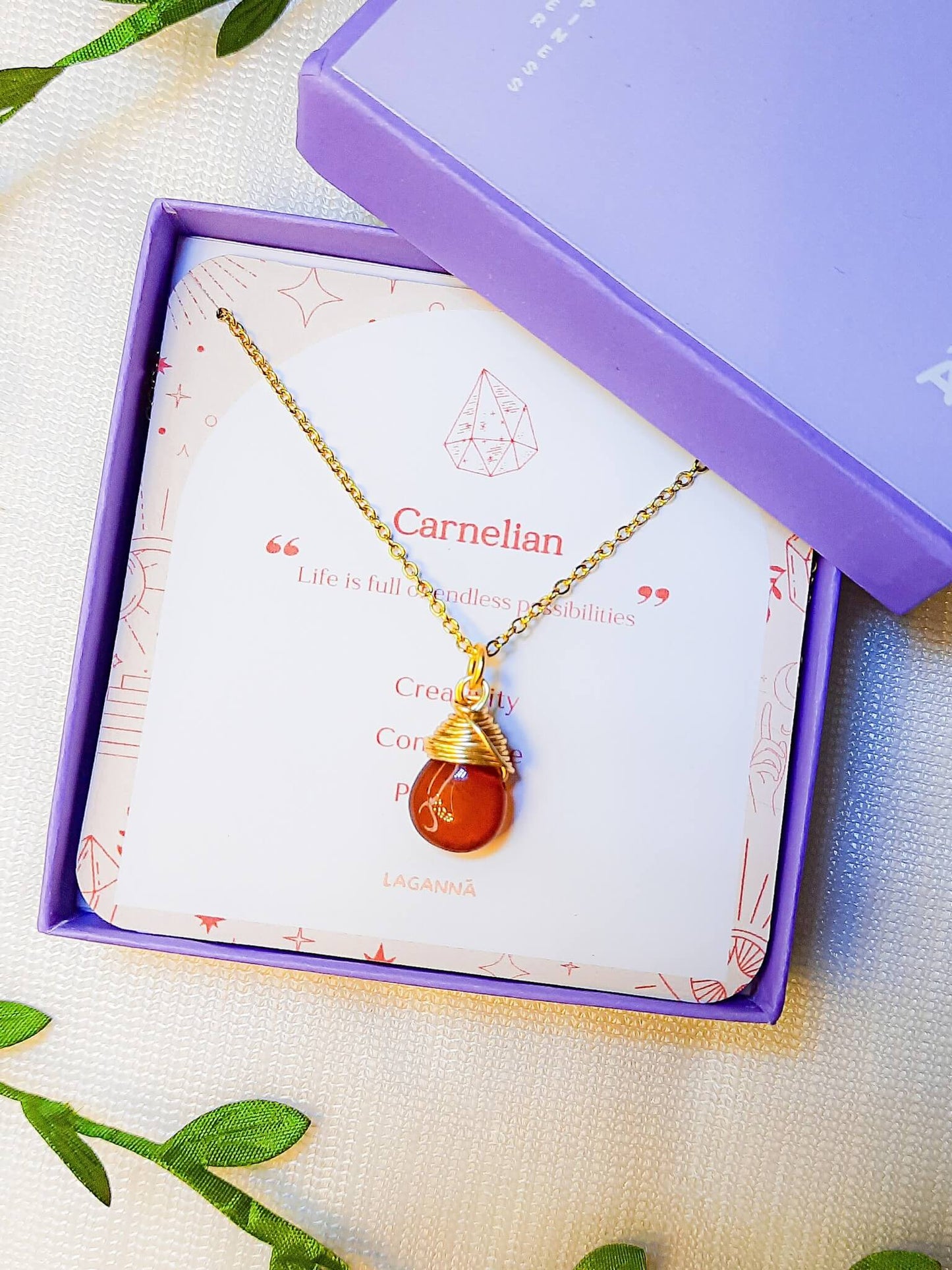 Handmade carnelian drop necklace in elegant jewelry box with natural leaves, gold wire wrapped healing crystal pendant featuring Sri Lankan spiritual jewelry craftsmanship perfect as boho gemstone statement necklace and protective amulet for confidence and creative energy with premium packaging