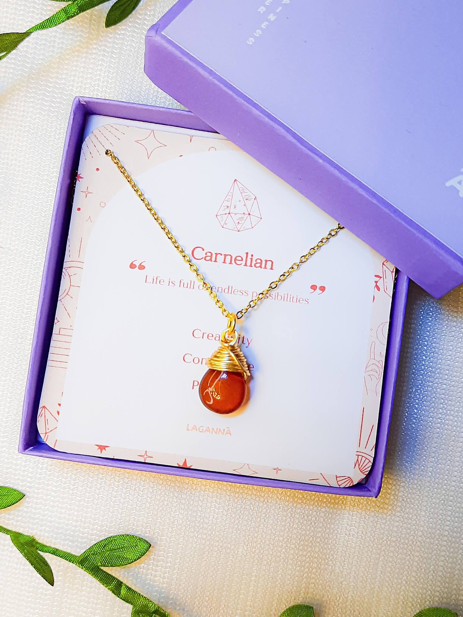 Handmade carnelian drop necklace in elegant jewelry box with natural leaves, gold wire wrapped healing crystal pendant featuring Sri Lankan spiritual jewelry craftsmanship perfect as boho gemstone statement necklace and protective amulet for confidence and creative energy with premium packaging