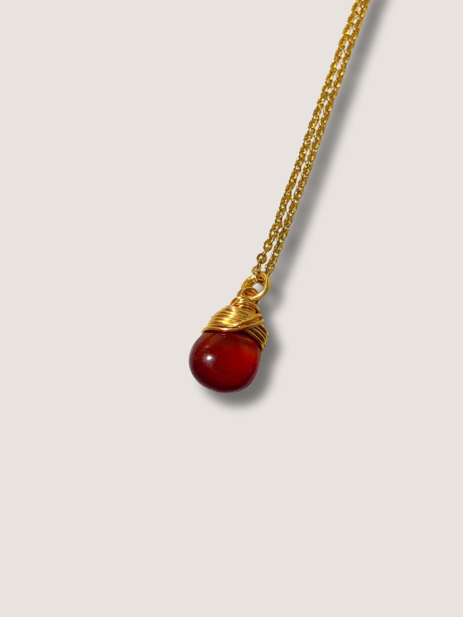 Carnelian drop necklace close-up detail showing handmade gold wire wrapped healing crystal pendant, natural orange gemstone jewelry crafted by Sri Lankan artisans featuring intricate metalwork perfect as spiritual statement necklace for confidence and creative energy activation