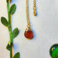 Gold carnelian drop necklace with natural green leaves showcasing handmade healing crystal pendant jewelry, Sri Lankan artisan spiritual necklace with wire wrapped design perfect as boho gemstone statement piece for nature-loving metaphysical jewelry enthusiasts seeking creativity and courage