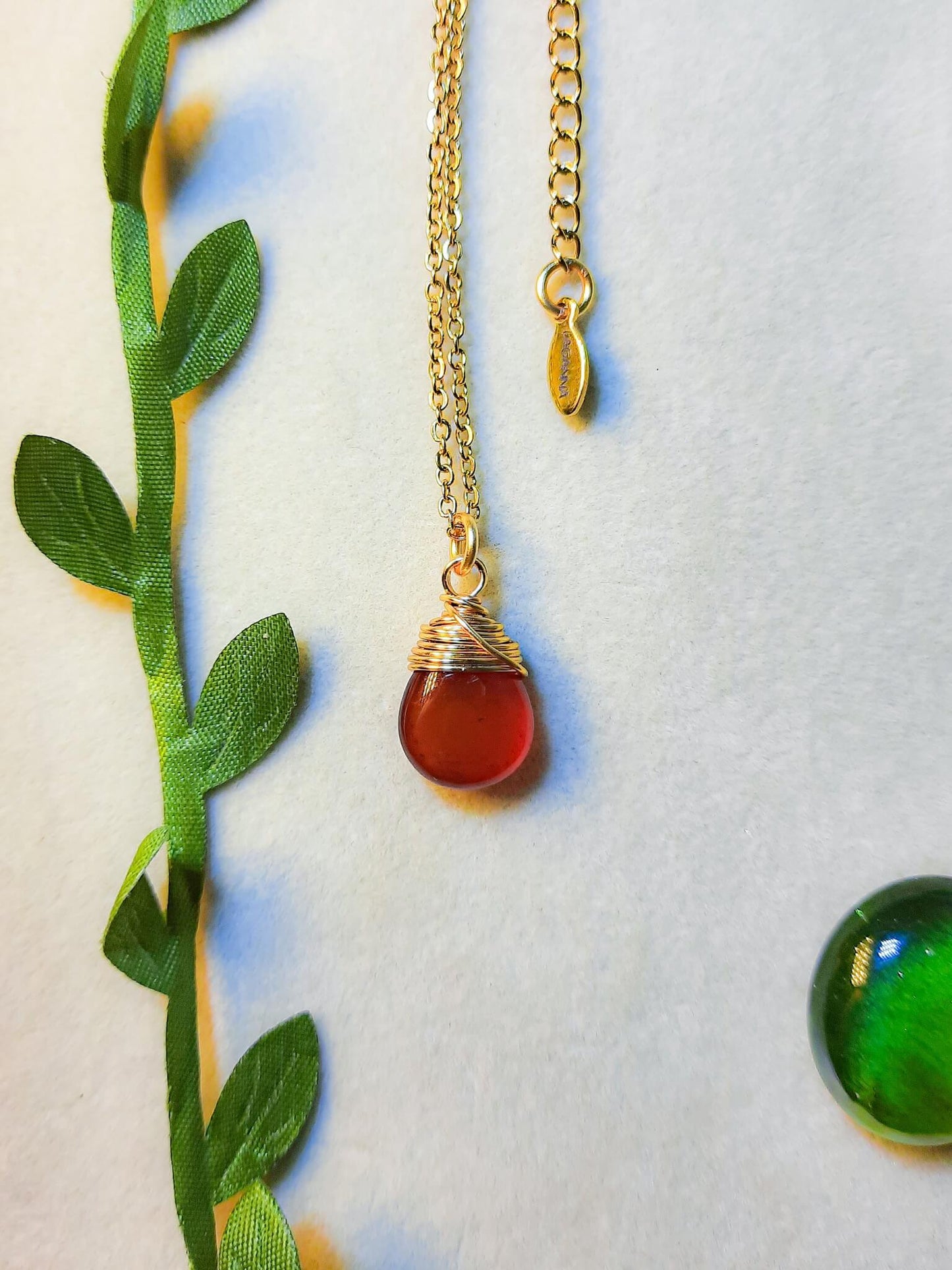 Gold carnelian drop necklace with natural green leaves showcasing handmade healing crystal pendant jewelry, Sri Lankan artisan spiritual necklace with wire wrapped design perfect as boho gemstone statement piece for nature-loving metaphysical jewelry enthusiasts seeking creativity and courage