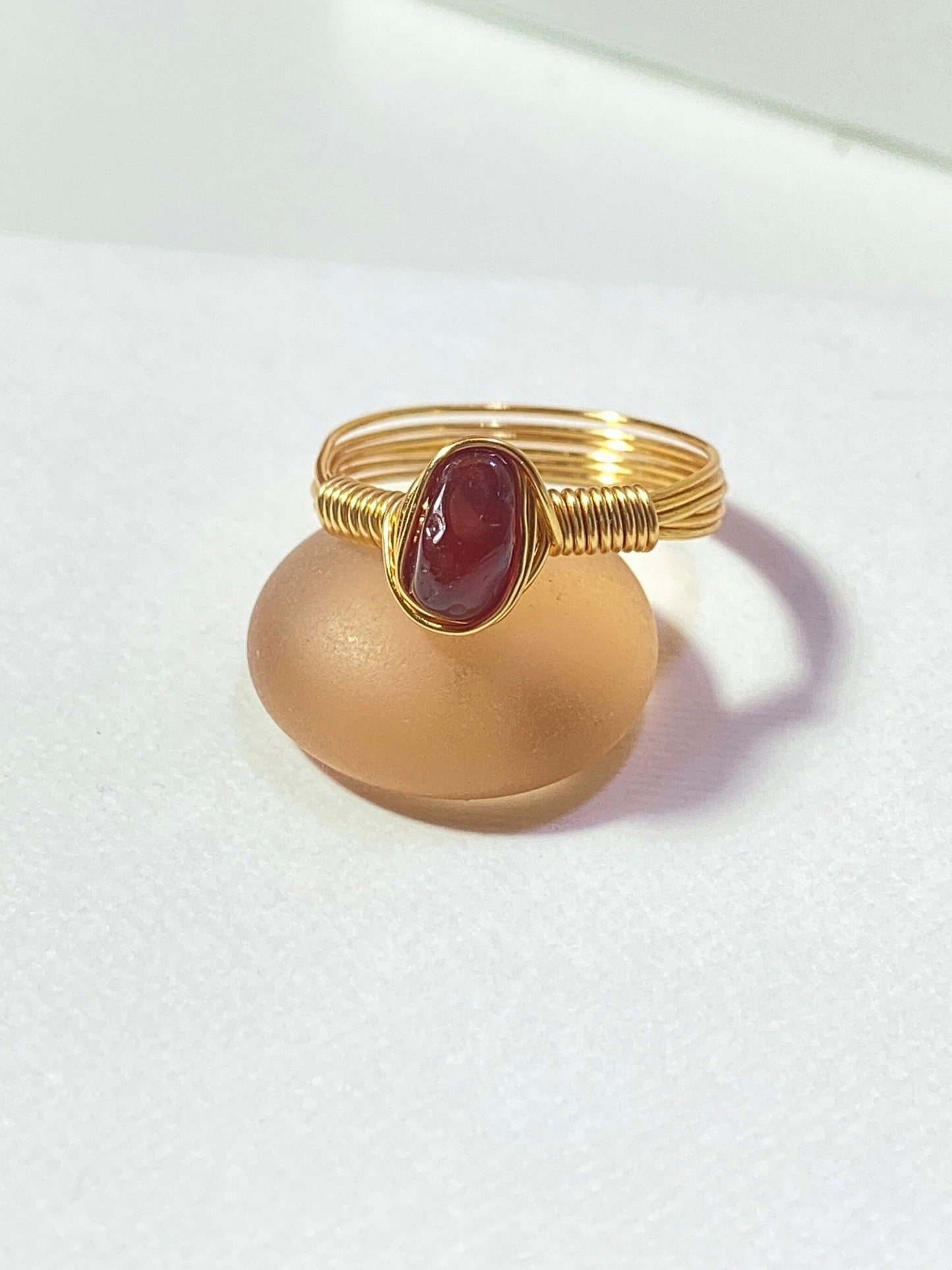 Natural carnelian irregular stone ring on white background showing handmade gold wire wrapped healing crystal jewelry, Sri Lankan artisan creativity stone ring featuring raw orange gemstone perfect as boho courage ring and sacral chakra amulet for confidence and motivation energy activation