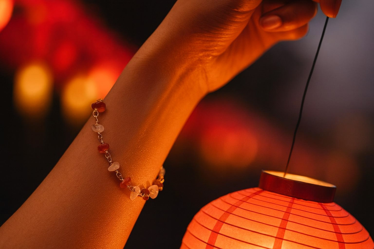 Chinese Red Lantern Bracelet worn while lighting traditional red paper lantern in magical evening atmosphere