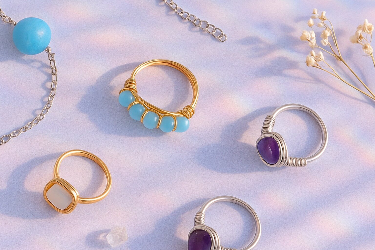 Clean cheerful aesthetic flat lay featuring Blue Moon frosted agate bracelet, Blue Chalcedony braided ring, Opalite square stone ring, Purple Jade irregular stone ring, and Amethyst irregular stone ring in magical surprise-gift styling
