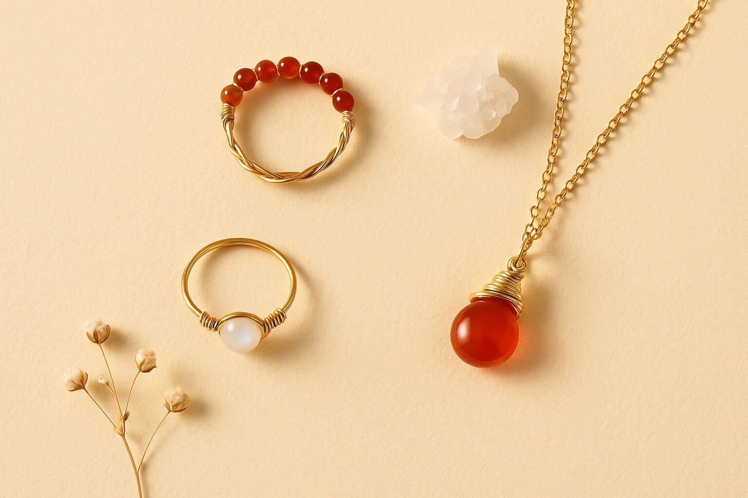 Clean empowering aesthetic flat lay featuring Carnelian braided ring, Dainty round moonstone ring, and Carnelian drop necklace in inspiring self-care styling