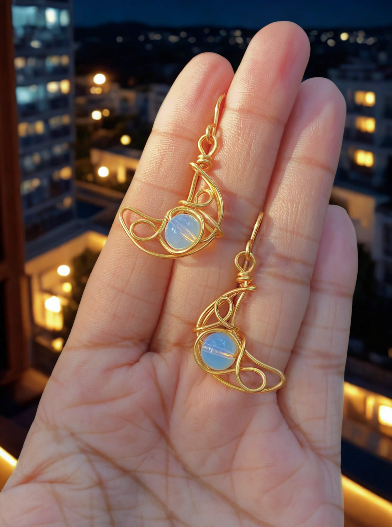 Stunning Crescent Moon Dangle Earrings showcasing Opalite's ethereal glow, handmade gold wire wrapped celestial jewelry from Sri Lanka by Laganna, shown on hands as mystical bohemian accessories