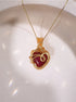 Red Chalcedony heart-shaped crystal pendant with detailed gold wire wrap on delicate chain, styled on white ceramic dish – artisan handcrafted necklace by Laganna Sri Lanka
