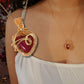Close-up of Red Chalcedony heart pendant with intricate gold wire wrapping worn by model against floral background – handmade passion and devotion necklace by Laganna, Sri Lankan crystal jewelry
