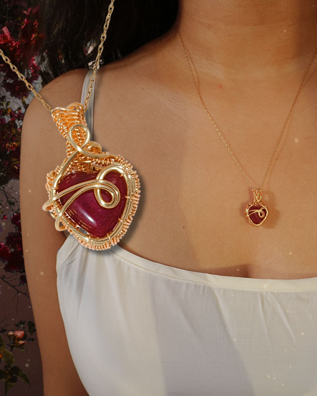 Close-up of Red Chalcedony heart pendant with intricate gold wire wrapping worn by model against floral background – handmade passion and devotion necklace by Laganna, Sri Lankan crystal jewelry
