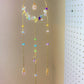 Crystal blessing suncatcher hanging display showing rainbow prism light effect with rose quartz, amethyst, citrine, aquamarine, fluorite, green aventurine, purple jade and clear quartz beads wire-wrapped in gold - handmade bohemian window decoration from Sri Lanka for healing energy and joy