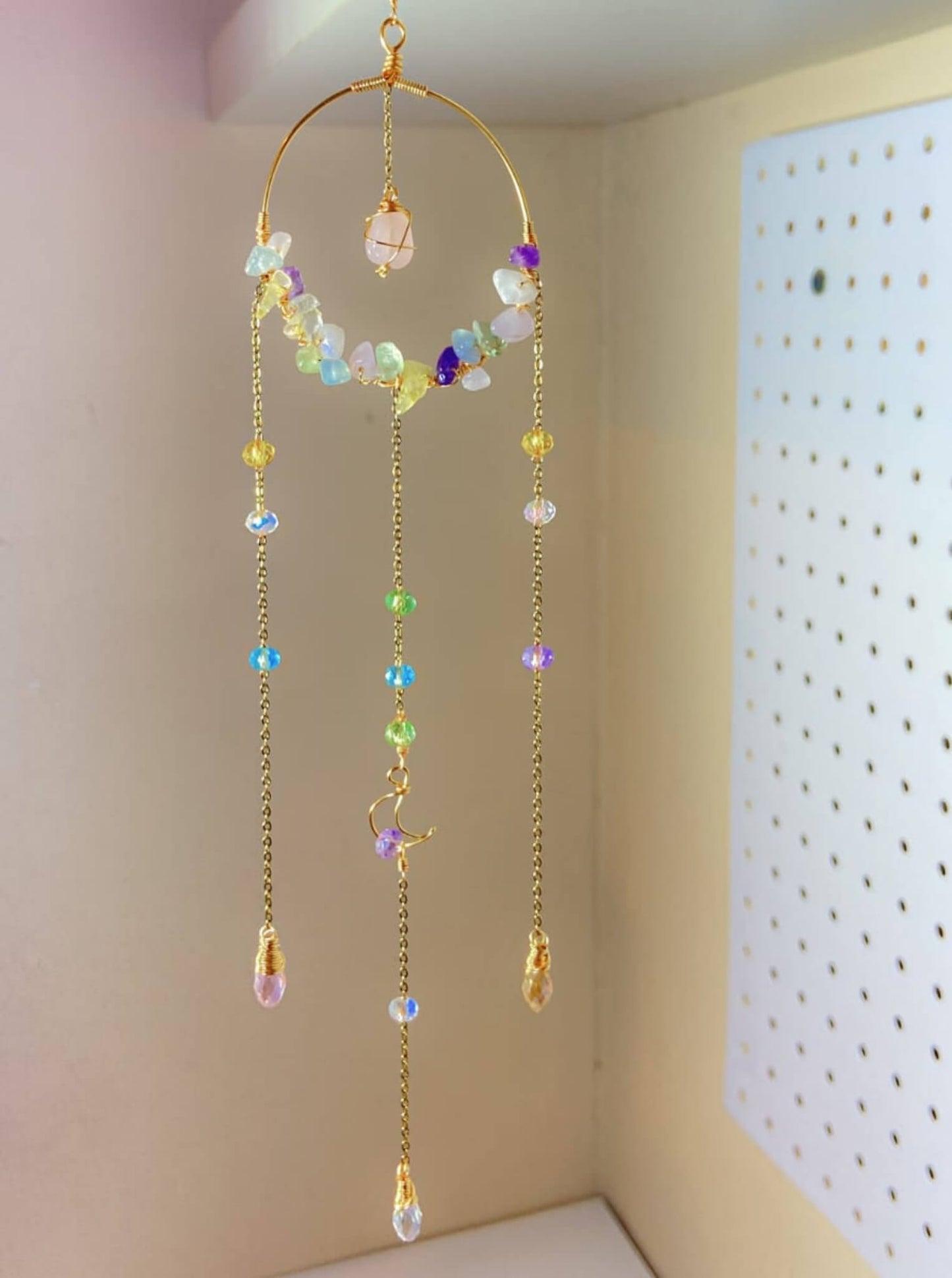 Crystal blessing suncatcher hanging display showing rainbow prism light effect with rose quartz, amethyst, citrine, aquamarine, fluorite, green aventurine, purple jade and clear quartz beads wire-wrapped in gold - handmade bohemian window decoration from Sri Lanka for healing energy and joy