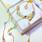 Crystal blessing suncatcher with rose quartz, amethyst, citrine, aquamarine, fluorite crystals in aesthetic flat lay styling with pastel packaging and zodiac cards - handmade Sri Lankan laganna healing crystal window decor for love, joy, and spiritual clarity