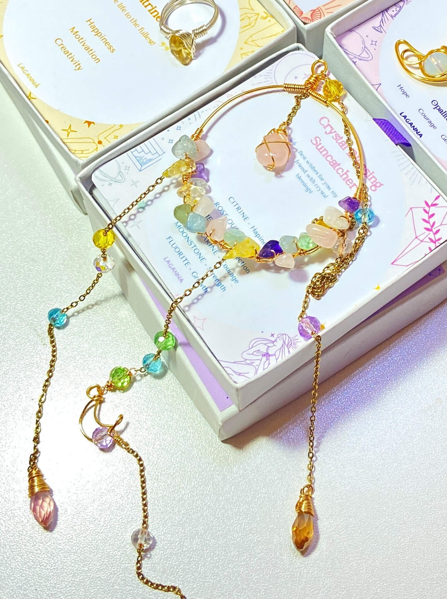 Crystal blessing suncatcher with rose quartz, amethyst, citrine, aquamarine, fluorite crystals in aesthetic flat lay styling with pastel packaging and zodiac cards - handmade Sri Lankan laganna healing crystal window decor for love, joy, and spiritual clarity