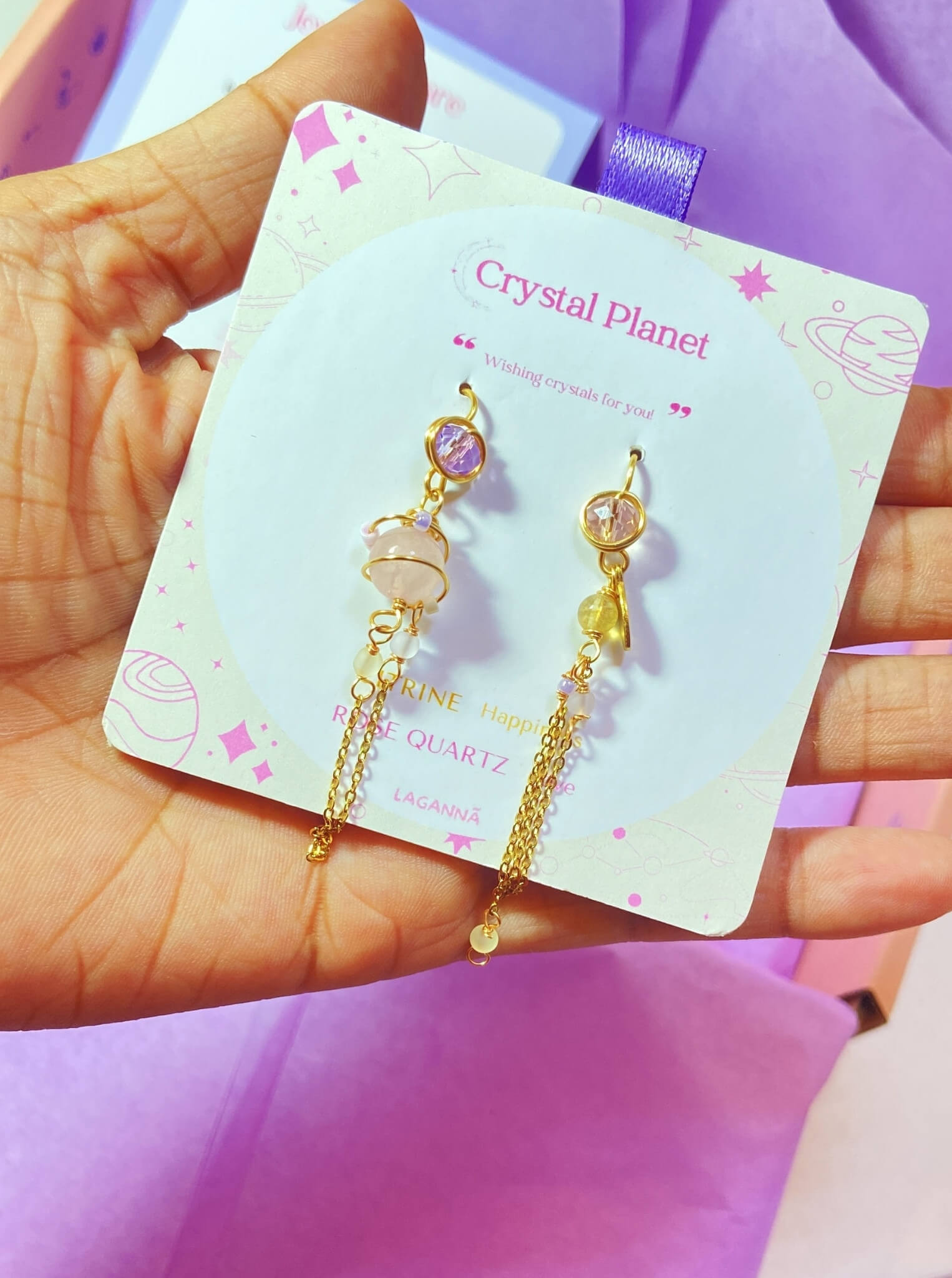 Crystal Planet mismatched dangle earrings jewelry card held on hand, handmade Sri Lankan rose quartz and citrine gold wire wrapped earrings gift