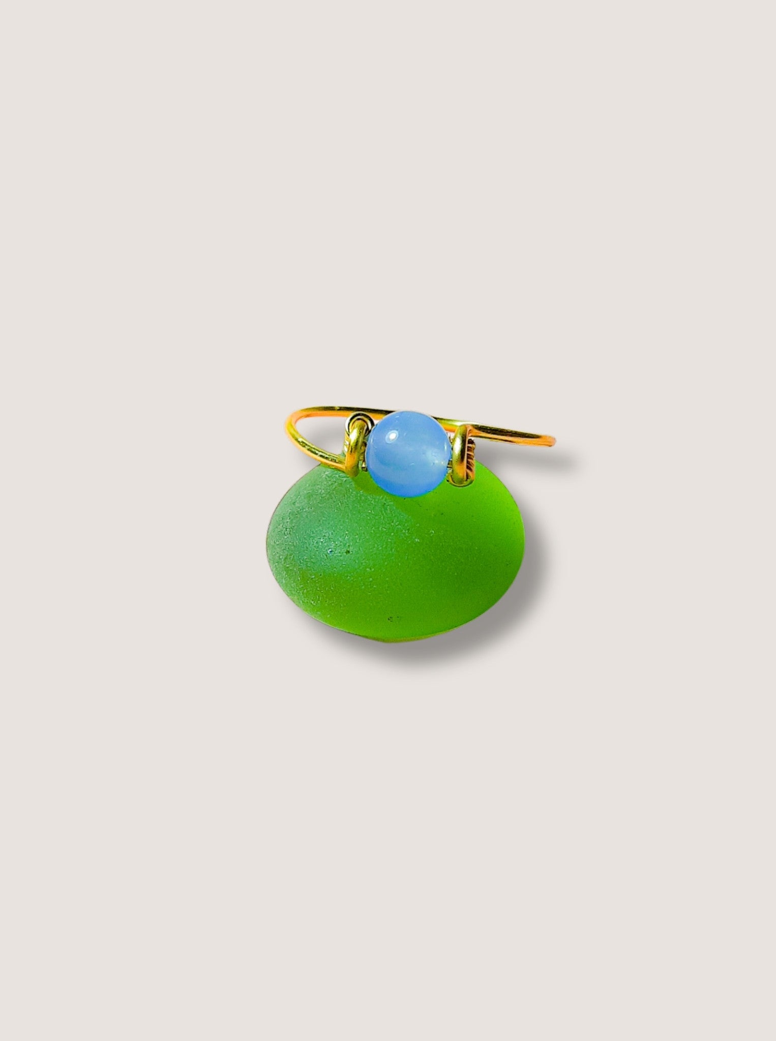 Dainty round blue chalcedony ring on light background showing gold wire wrapped design, handmade Sri Lankan healing crystal ring for throat chakra and peace
