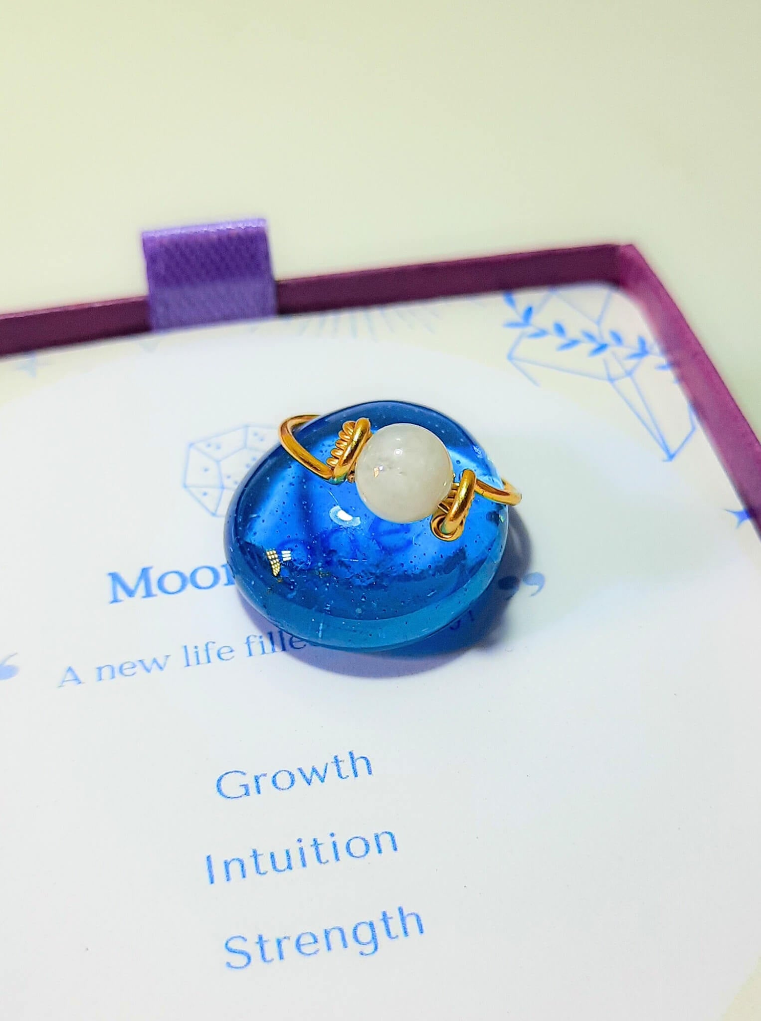 Dainty round moonstone ring closeup in jewelry box, handmade Sri Lankan gold wire wrapped healing crystal ring for intuition and inner wisdom