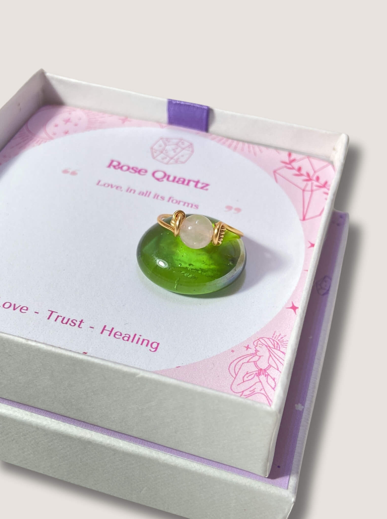 Dainty round rose quartz ring jewelry box on light background, handmade Sri Lankan gold wire wrapped healing crystal ring for emotional healing