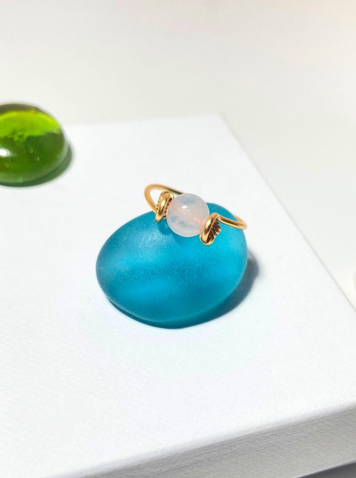  Dainty round rose quartz ring on light background with aesthetic styling, handmade Sri Lankan healing crystal ring for heart chakra and self-love