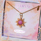 Purple Angelite Eternal Sun Necklace with a gold wire sun pendant in a Laganna gift box, displayed on its Peace, Calm, Guidance card with a floral border.
