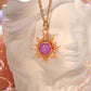 Eternal Sun Necklace with a round Purple Angelite stone and gold wire sun rays, displayed on a small white statue, handmade in Sri Lanka by Laganna.
