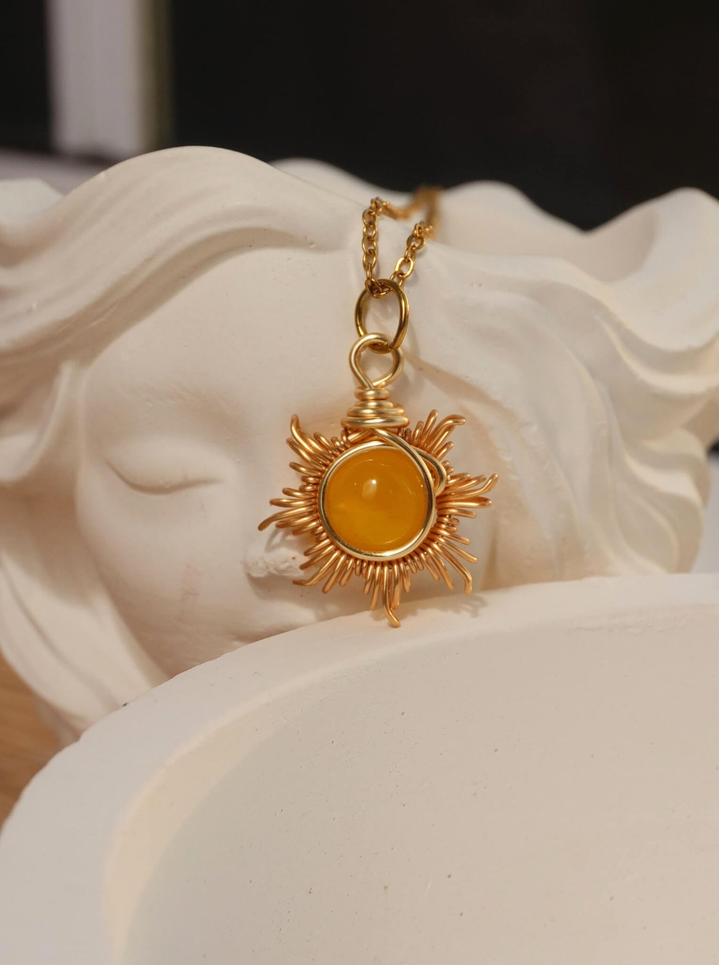 Eternal Sun Necklace Yellow Onyx gold wire sun pendant resting on white goddess sculpture artistic flat lay, handmade healing crystal necklace Sri Lanka Laganna