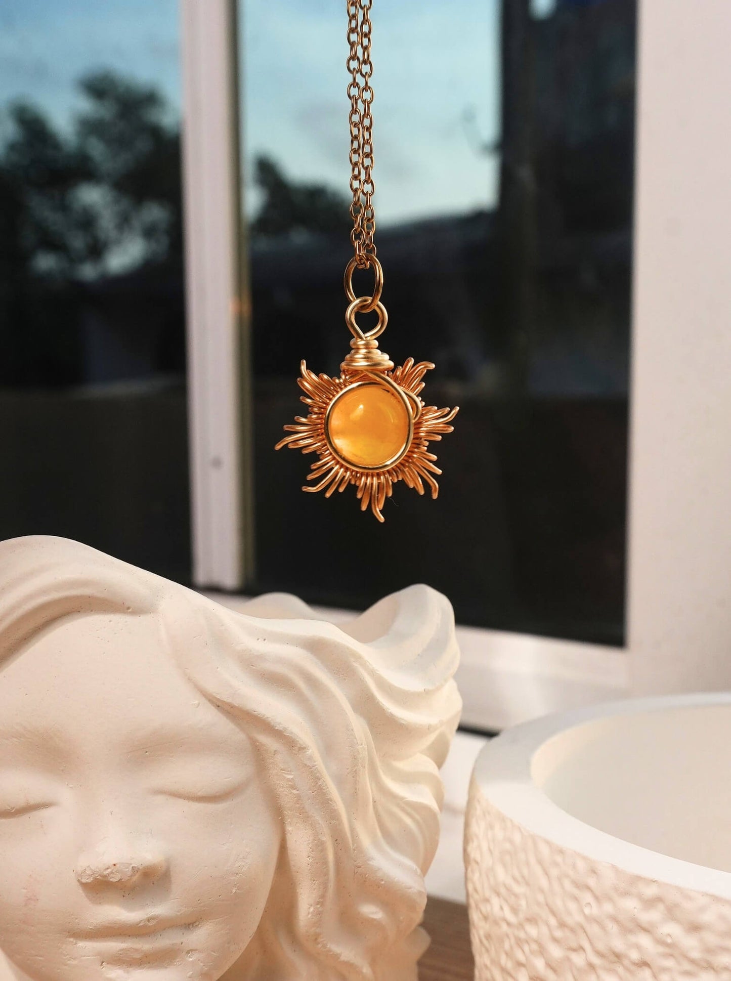 Eternal Sun Necklace Yellow Onyx gold wire wrapped sun pendant hanging near white goddess sculpture window light, handmade healing crystal jewelry Sri Lanka Laganna