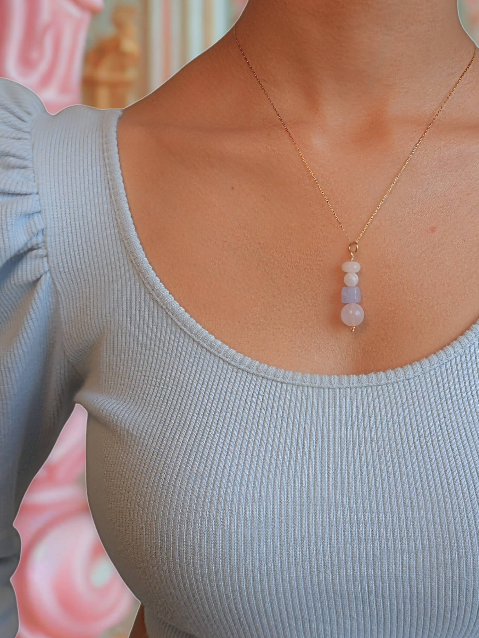 French Palace Column Necklace handmade wire wrapped crystal jewelry featuring rose quartz aquamarine moonstone yellow jade pastel stones worn on model with powder blue ruffled top soft pink palace interior background inspired by 18th century Rococo Versailles French court elegance Marie Antoinette era romantic feminine design artisan crafted Sri Lanka Laganna healing crystals love courage intuition joy new beginnings timeless wearable fairytale charm