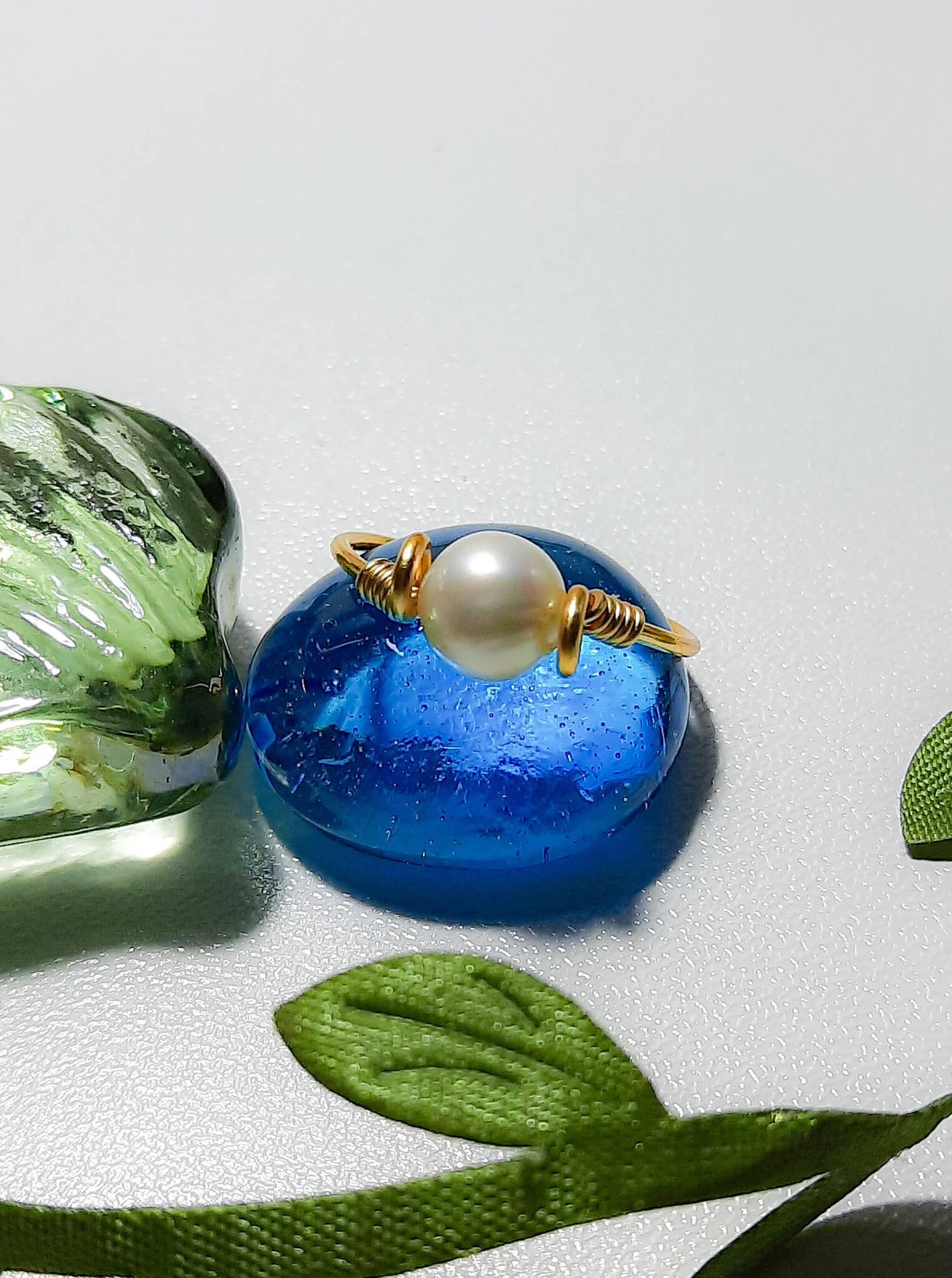 Handmade freshwater pearl dainty ring in gold wire wrap on white background display, Sri Lankan artisan pearl jewelry for elegance, purity, and feminine energy enhancement