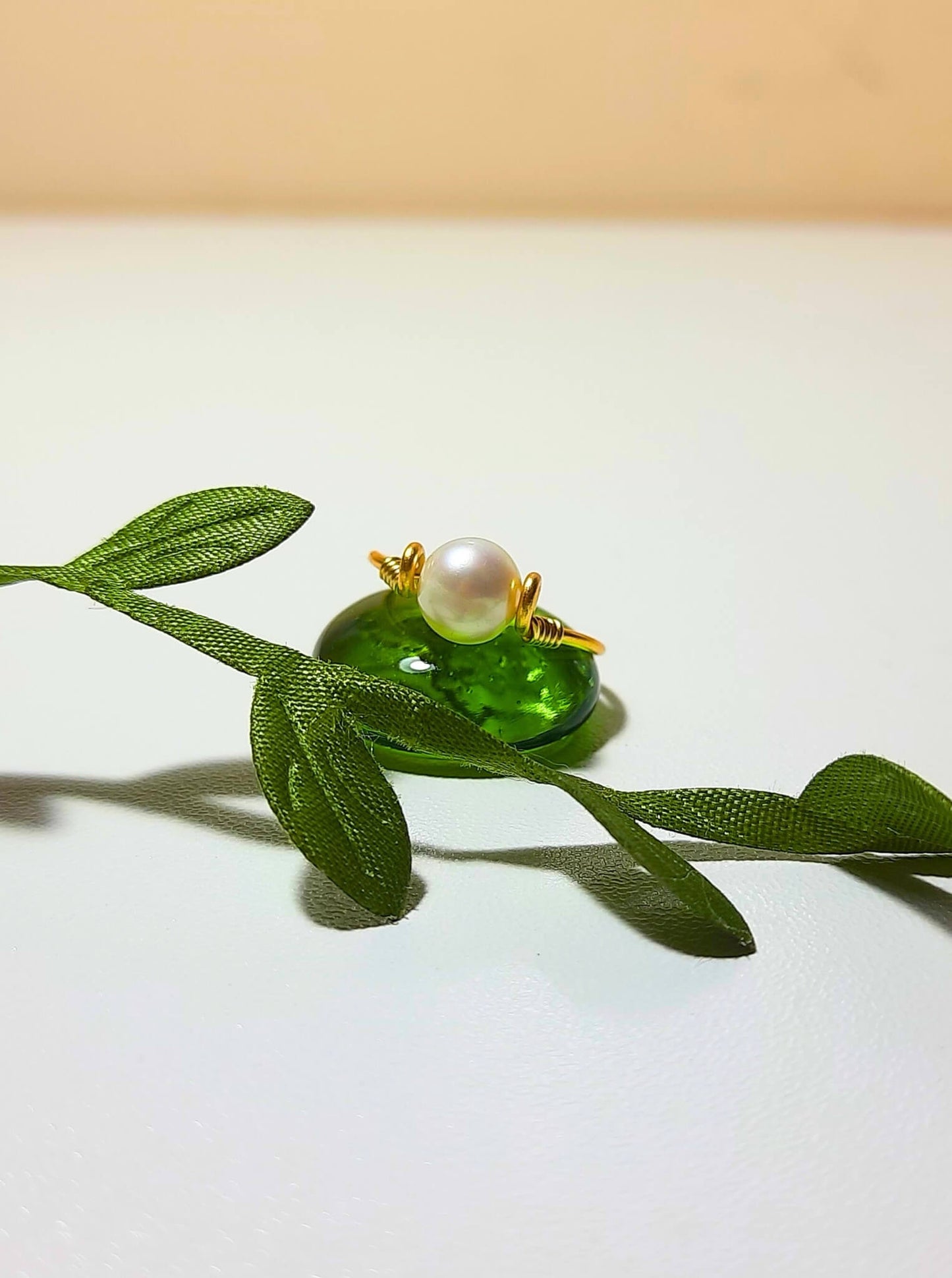 Natural freshwater pearl dainty ring in gold wire wrap on white background with leaf detail styling, handmade Sri Lankan pearl jewelry for purity, wisdom, and calming energy